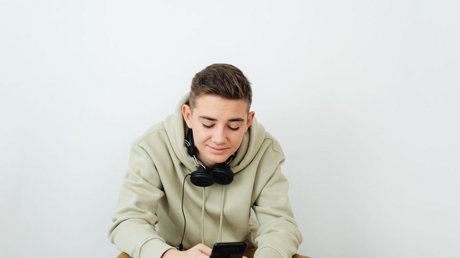 A producer with headphones around his neck working on a phone