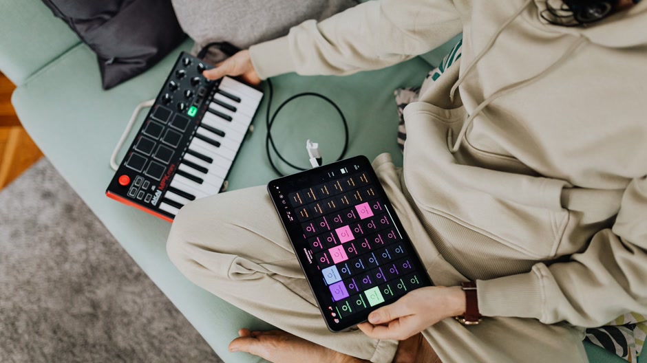 Producer playing a MIDI keyboard while a DAW runs on screen