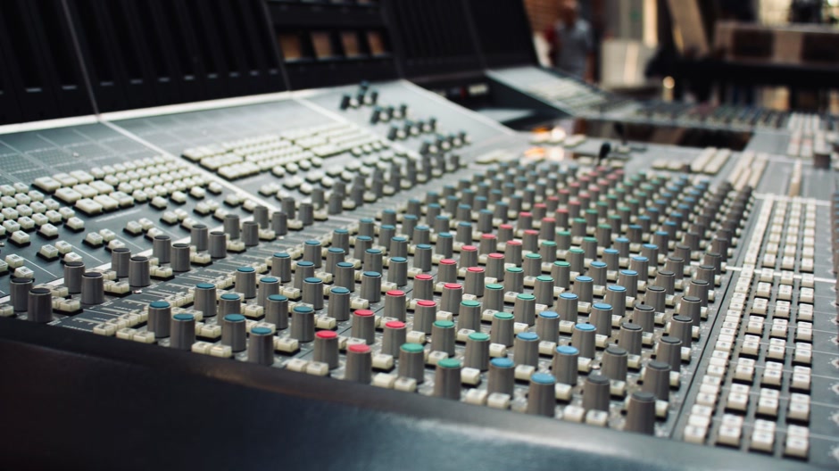 Faders on a mixing console in a dimly lit studio