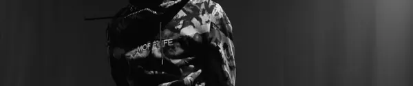 A rapper in a camouflage hoodie holding a microphone while freestyling, in black and white