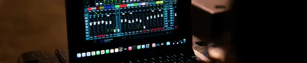 A sound engineer adjusting an audio mixer while working on a laptop
