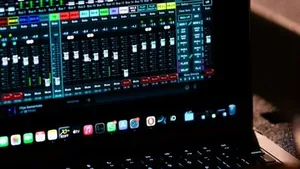 A sound engineer adjusting an audio mixer while working on a laptop