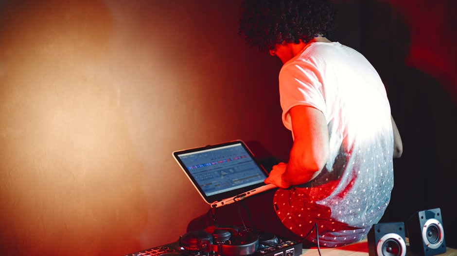 A laptop and a mixer on a desk in a dim room