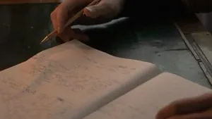 Person writing rap lyrics in a notebook next to a laptop
