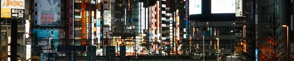 Shinjuku street at night seen from above, neon signs and traffic