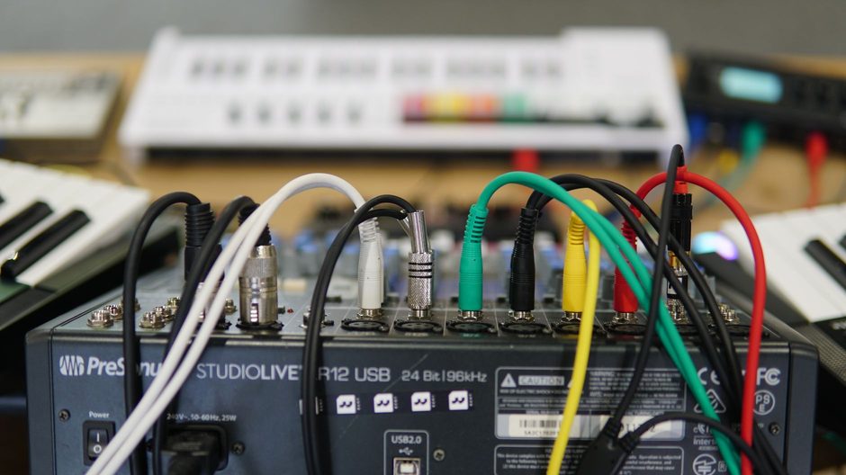 Rear panel of a studio audio interface with cables plugged in