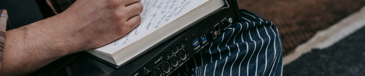 A person writing bars in a notebook during a studio session