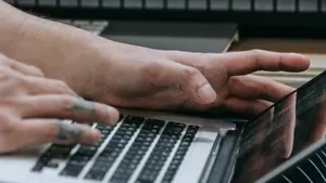 A producer working on a laptop in front of a keyboard and synth in a home studio