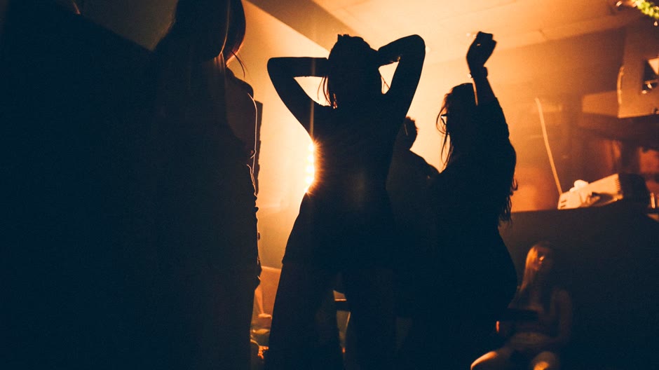 Crowd dancing in a dark club with warm stage light