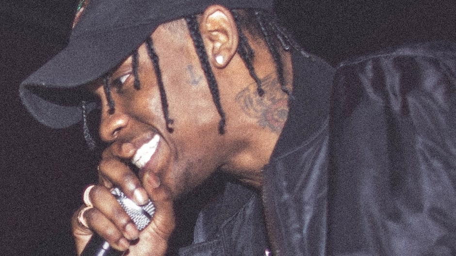 Travis Scott singing into a microphone on stage