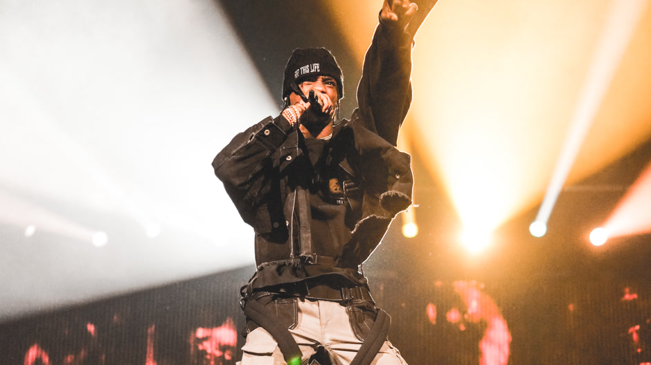 Travis Scott jumping on stage in front of a screen