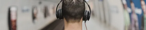 Homme casque sur les oreilles écoutant une chanson le long d'une voie ferrée au crépuscule