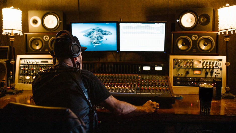 Producteur comparant deux instrumentales dans un studio sombre