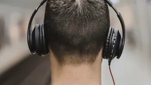 Man wearing headphones listening to a song beside a railway line at dusk