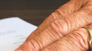 Hands signing a document on a wooden desk
