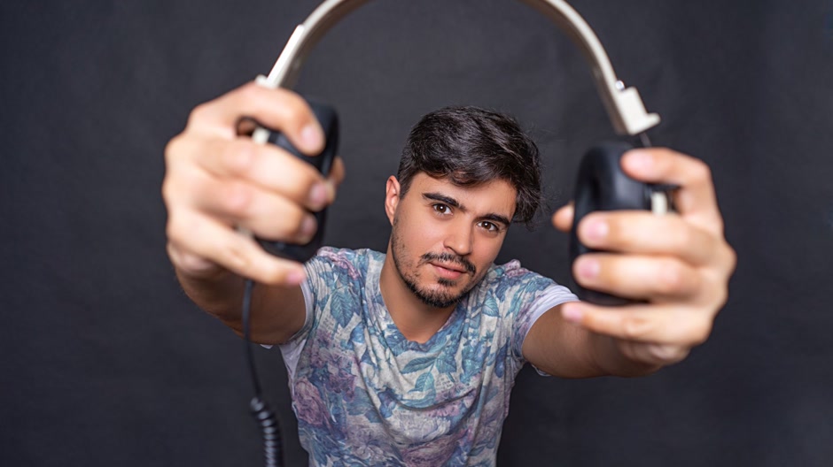 Man holding a pair of headphones in a dark room