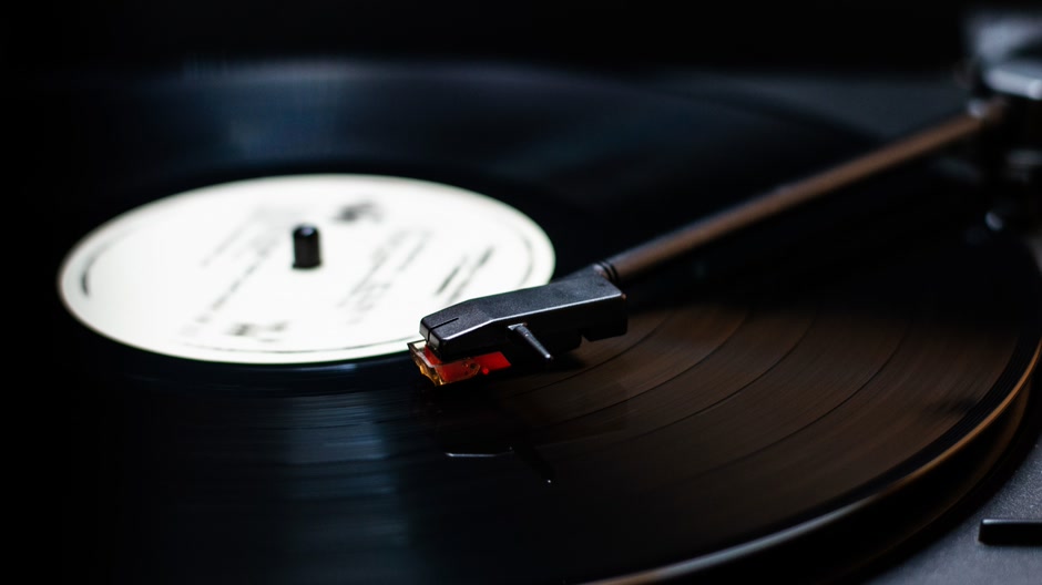 A black vinyl record spinning on a turntable in low light