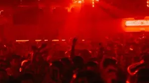 A crowd in a nightclub lit by red stage lights during a concert